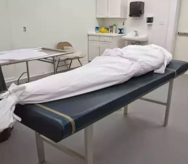 The masjid's washing room, with a body prepared in a white shroud on the table